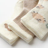 Close-up of fluffy sheep baby socks in soft beige, brown, and cream tones